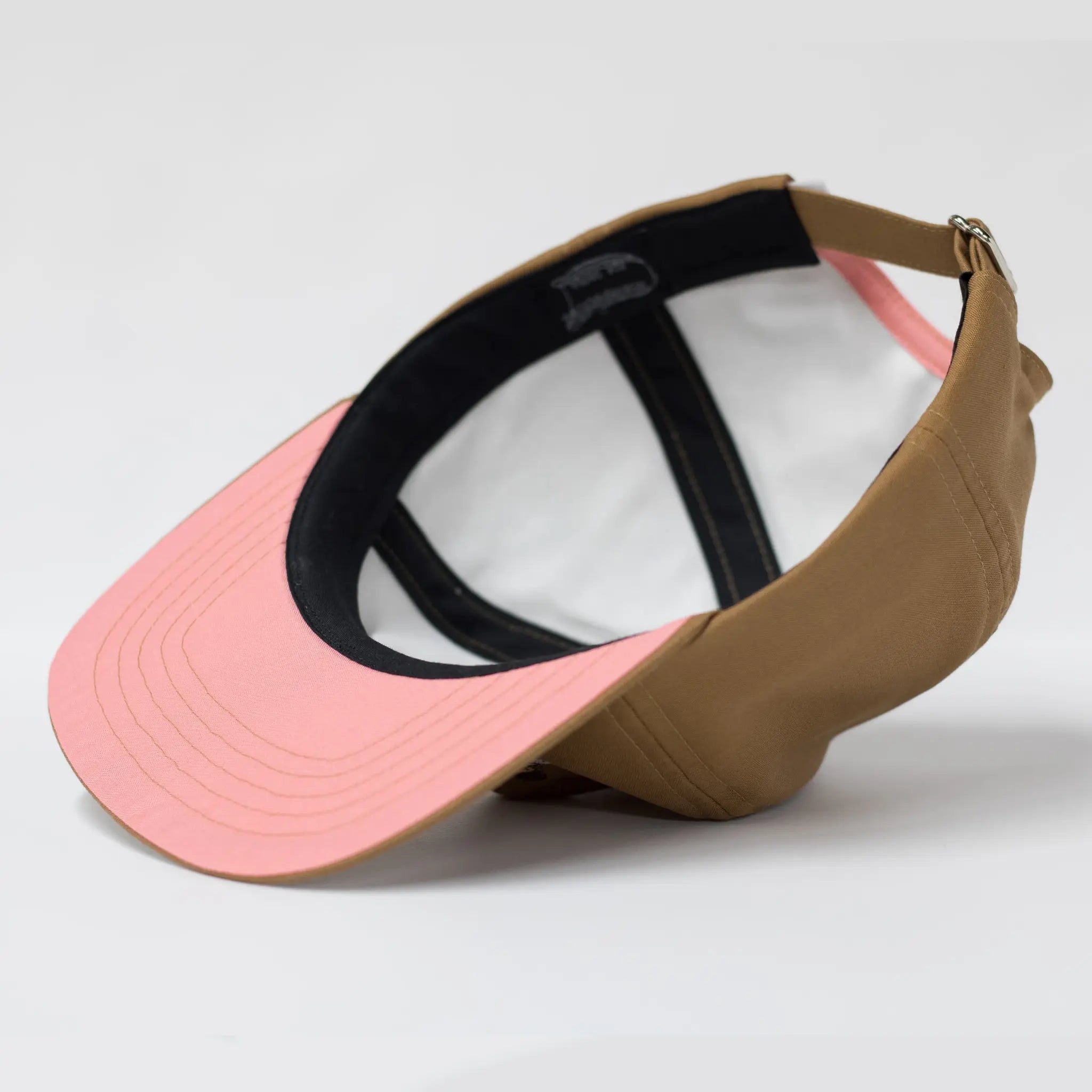 Underside view of a brown Regular Magic cap highlighting the contrasting pink underbrim, black sweatband, and internal panel construction.