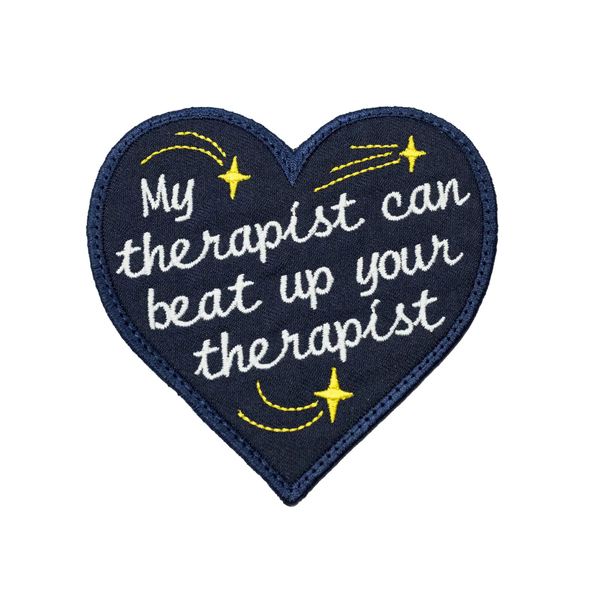 Dark blue heart-shaped embroidered patch by Regular Magic with the phrase 'My therapist can beat up your therapist' in white cursive script, surrounded by yellow stitched shooting stars.