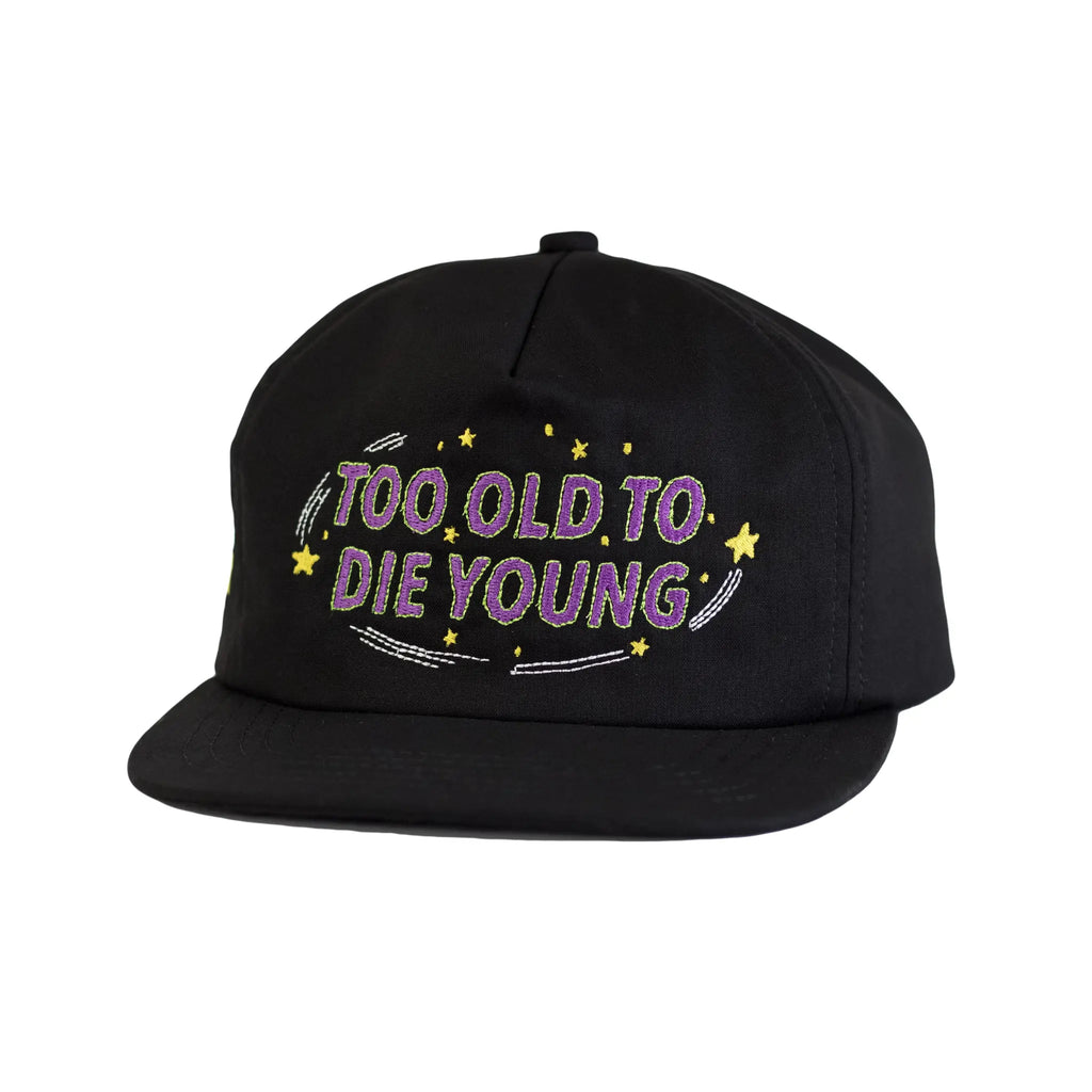 Front profile view of a black Regular Magic cap embroidered with the phrase 'TOO OLD TO DIE YOUNG' in purple text surrounded by yellow stars.
